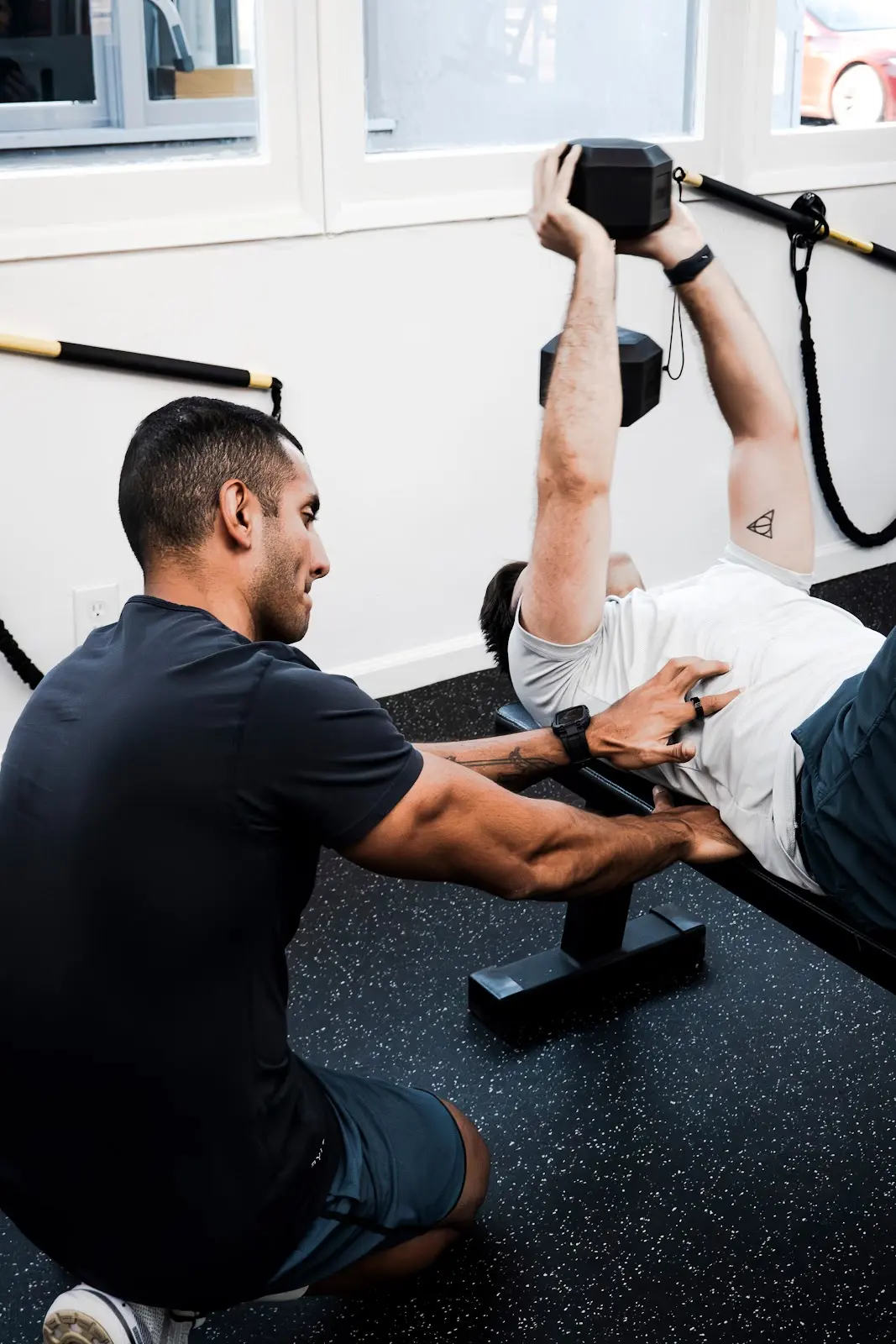 A coach spotting a dumbbell bench press during Pure Strength