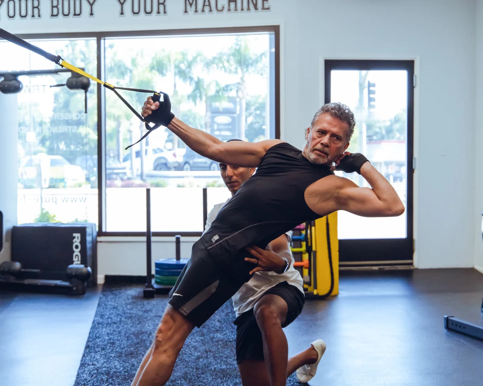 A coach guiding a client through TRX-assisted mobility work