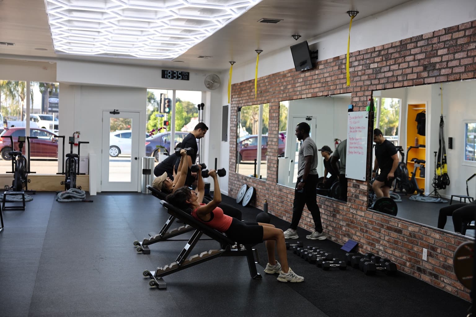 Clients performing incline dumbbell presses with coaches nearby in the Pure Function group-class studio